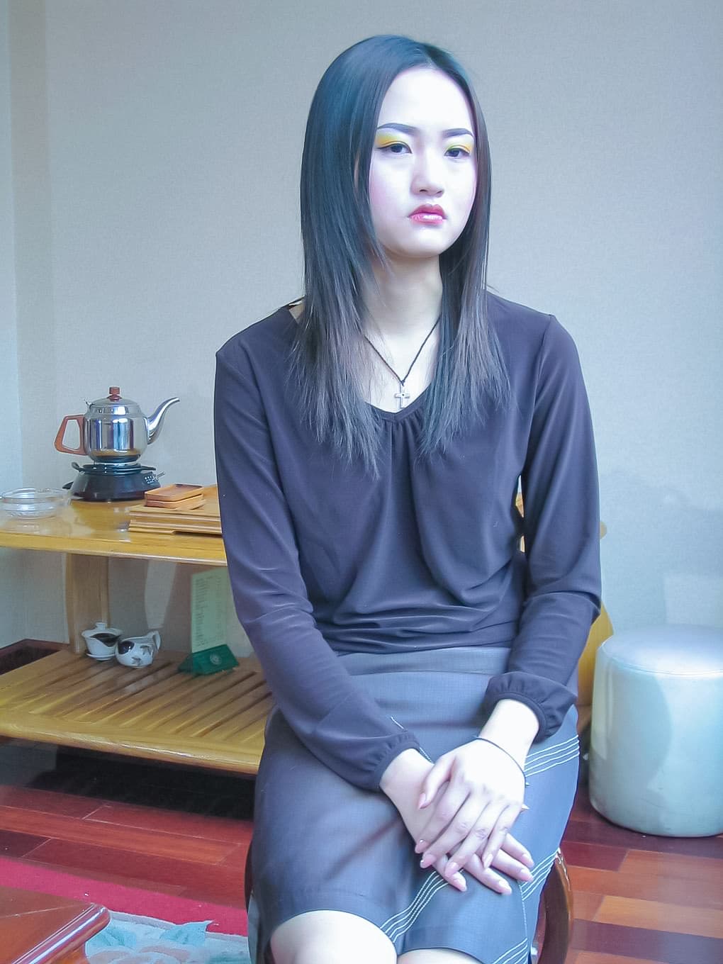 Close-up of Jingyao’s bare foot slipping into a strappy sandal, toenails glossed, ankle curve highlighted by soft indoor lighting